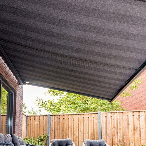 Store banne à toile sombre déployé sur une baie vitrée