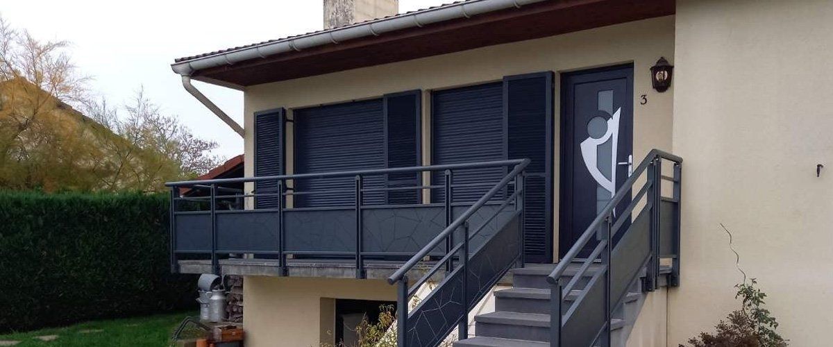 Extérieur d'un étage d'une maison avec escalier, garde-corps métallique sombre et menuiseries accordées