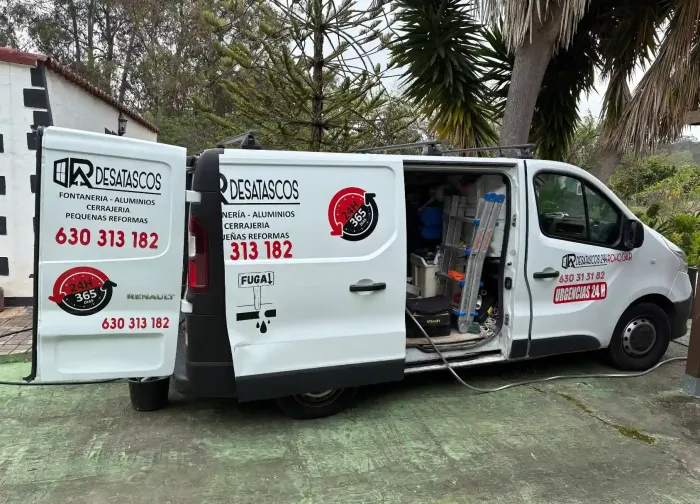 Hombre trabajando en un desagüe. Señal de precaución amarilla y equipo en un camino de hormigón, en una zona costera.