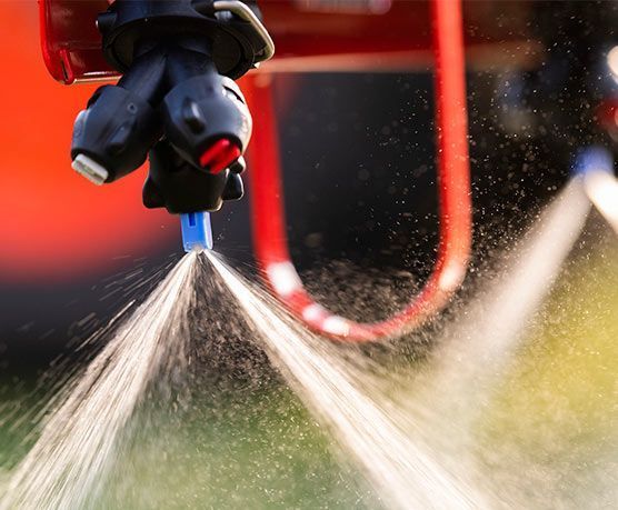 Un primer plano de un pulverizador rociando agua sobre un campo.