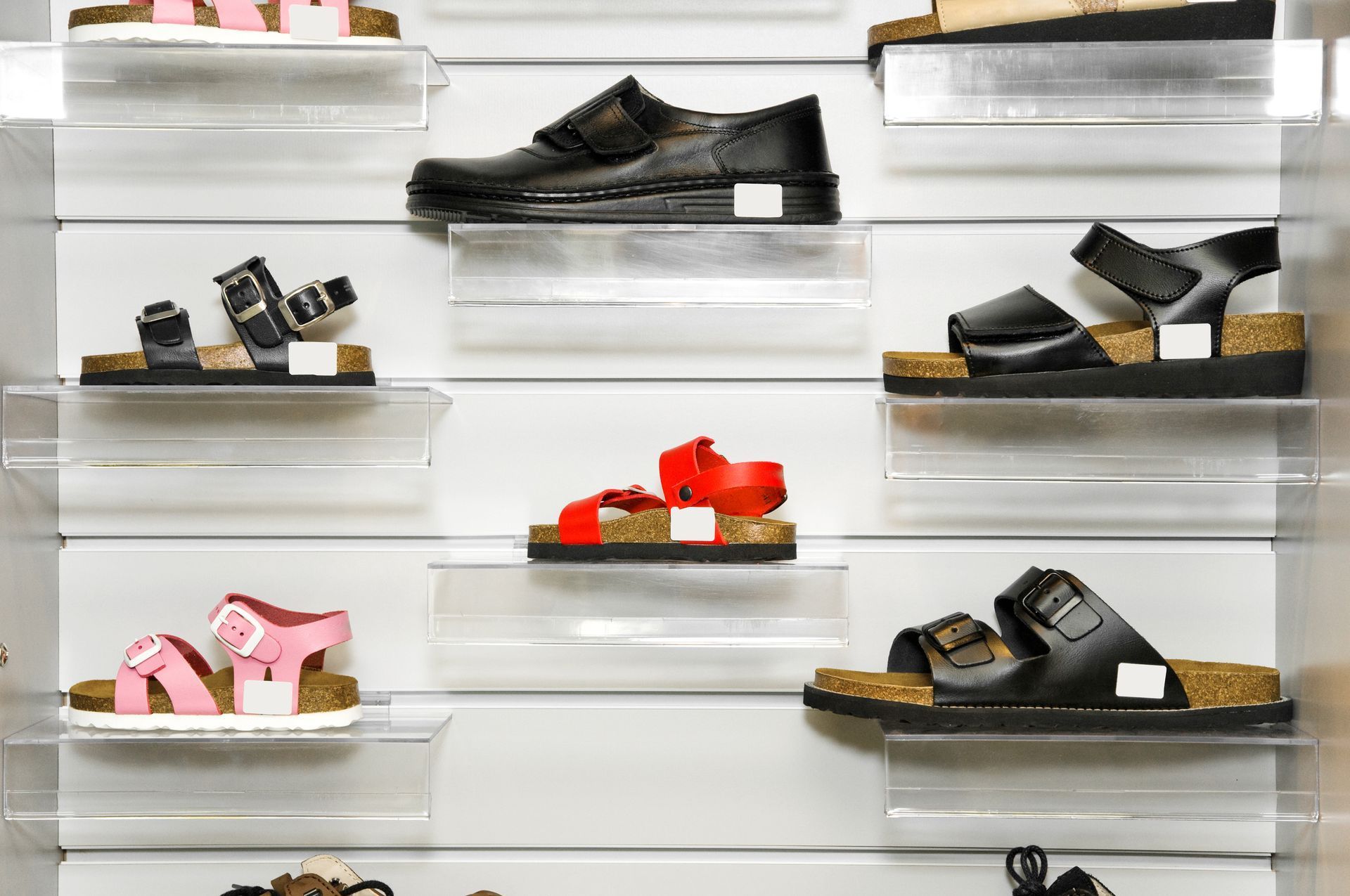 Des chaussures exposées en vitrine ; diverses sandales et chaussures disposées sur des étagères.