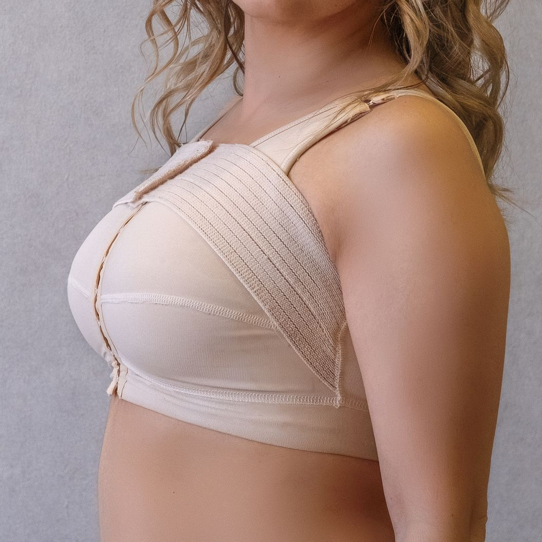 Femme de profil portant un soutien-gorge beige postopératoire à fermeture avant et larges bretelles.