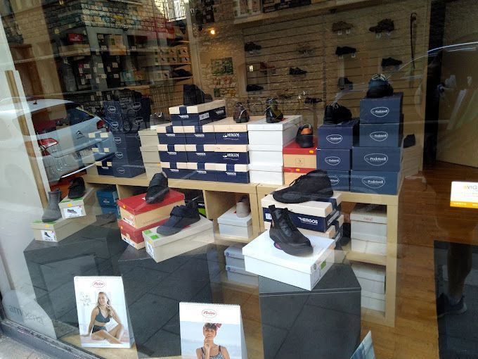 Vitrine d'un magasin de chaussures avec des boîtes à chaussures et des chaussures empilées.