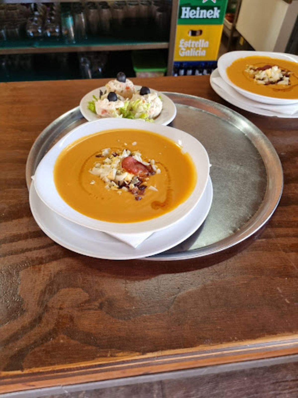 Dos tazones de sopa en una bandeja con una nevera portátil Heineken al fondo