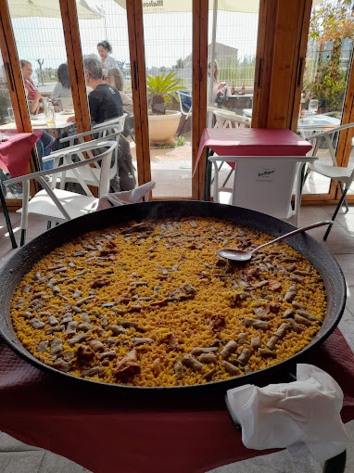Una gran cacerola con comida y una cuchara dentro está sobre una mesa.