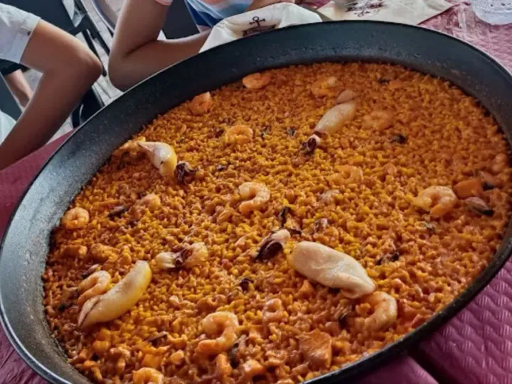 Una sartén llena de arroz y camarones reposa sobre una mesa.