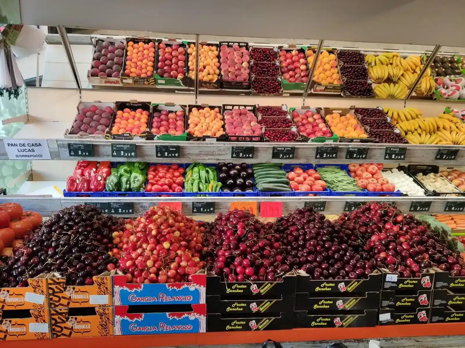 Exhibición colorida de frutas frescas variadas apiladas en cajas en un puesto del mercado.
