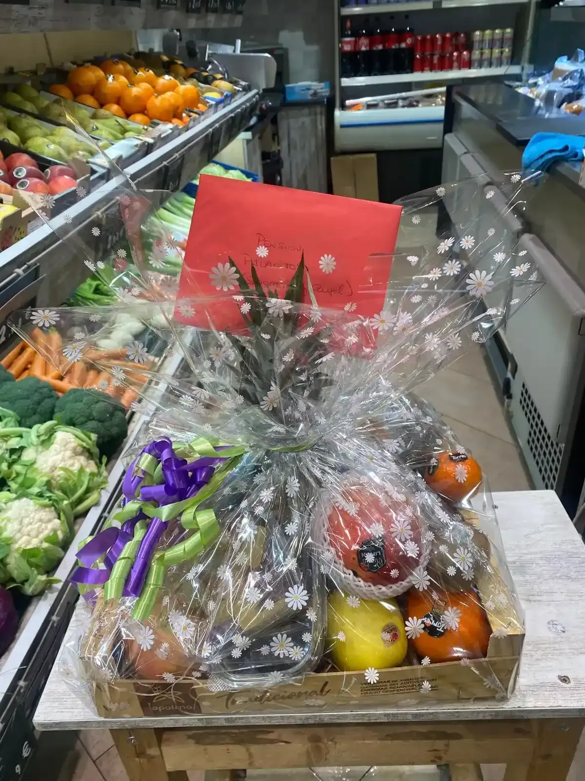 Cestas de regalo con frutas y aperitivos envueltos en celofán en un pasillo de un supermercado.