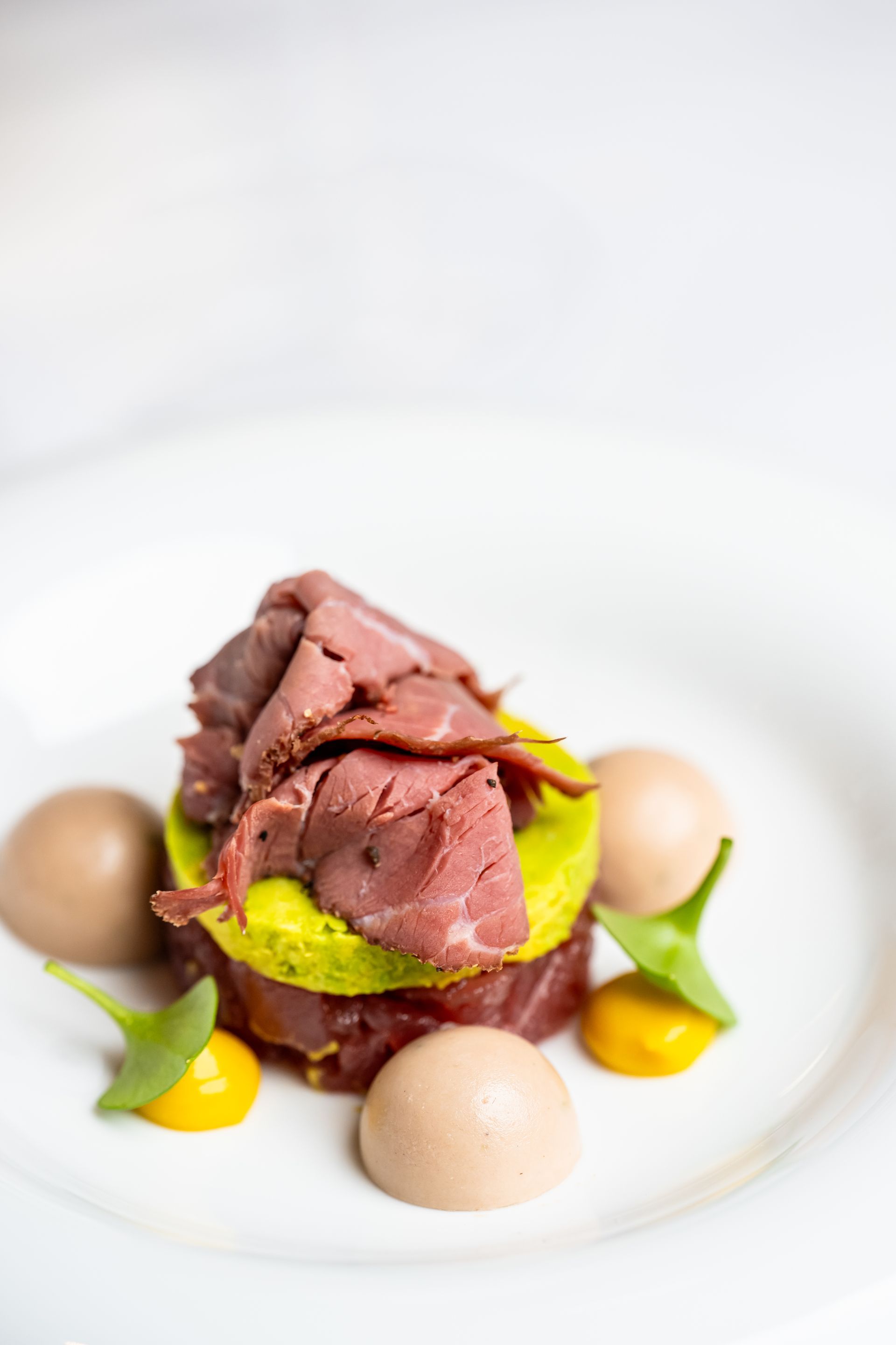 Een wit bord met vlees en groenten op een tafel.