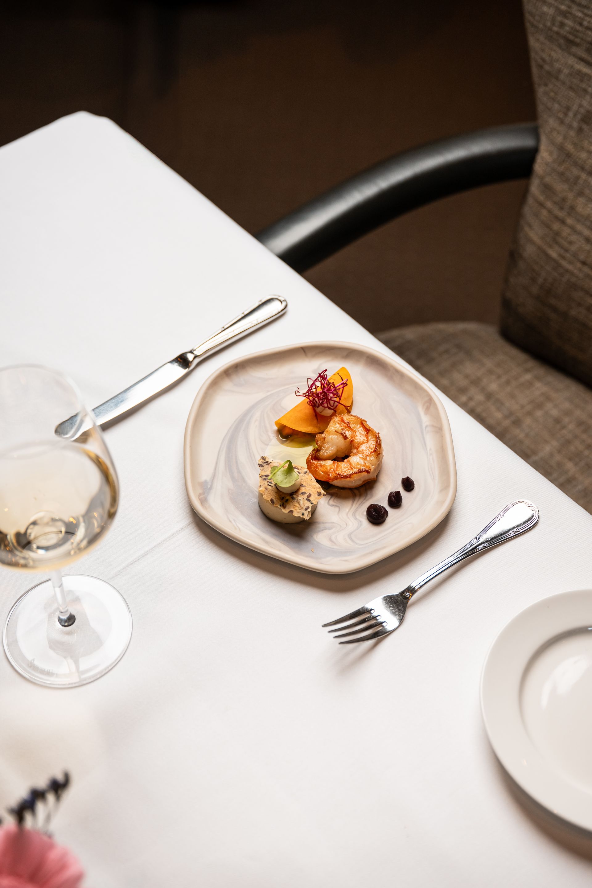 Er staat een bord met eten op tafel, naast een glas wijn.