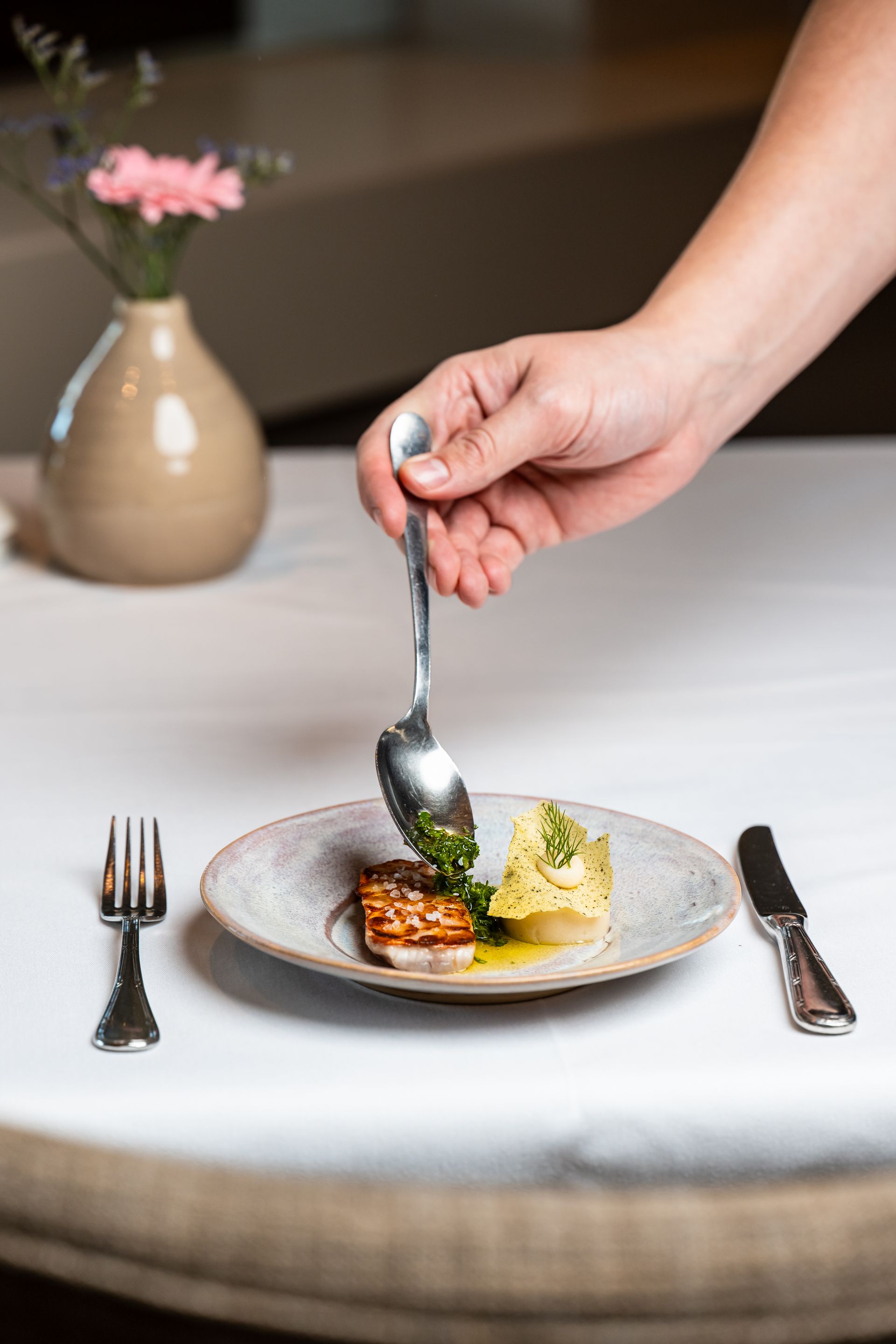 Een persoon houdt een lepel boven een bord met eten.