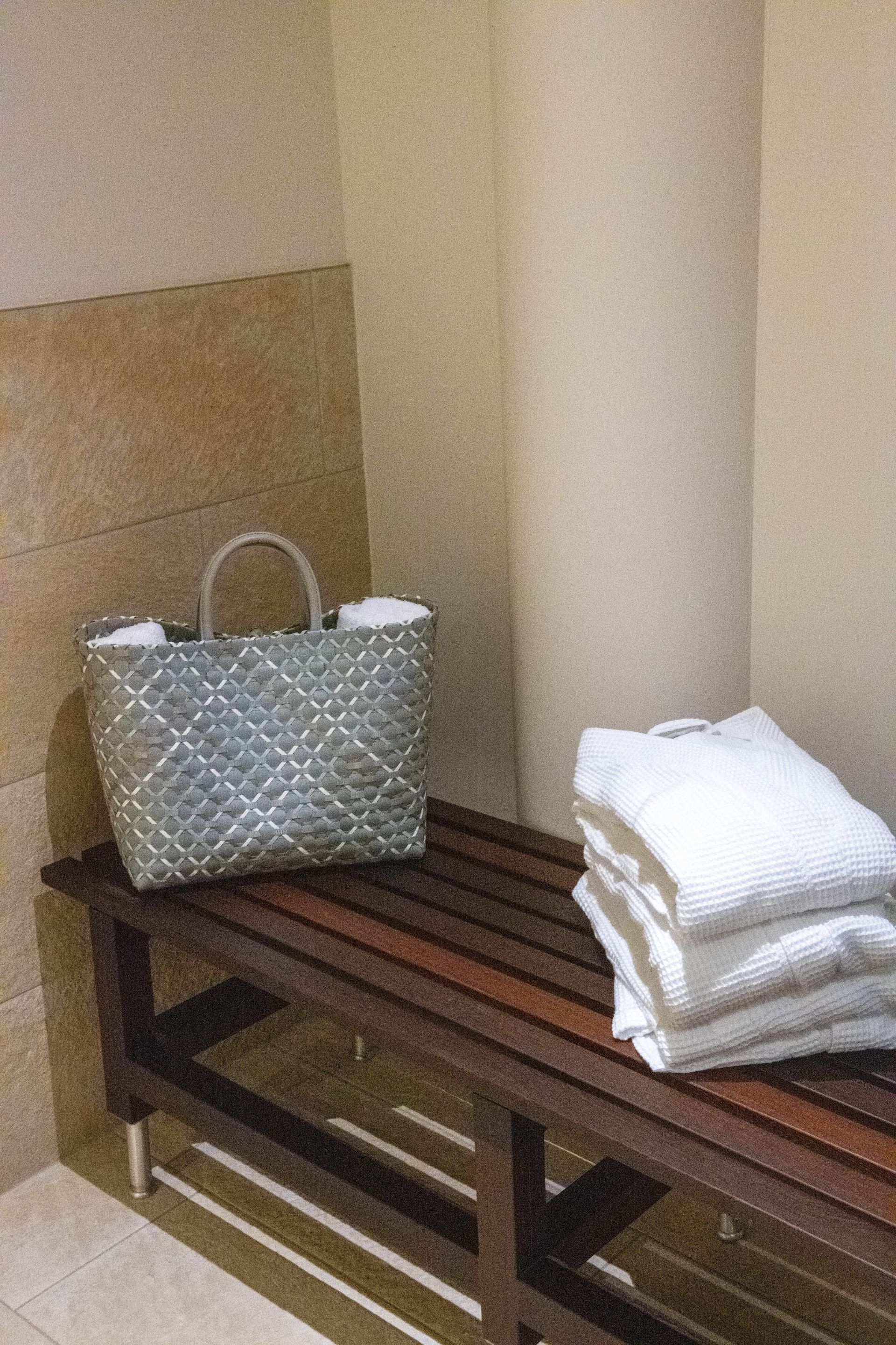 Een houten bank met handdoeken en een mand erop.