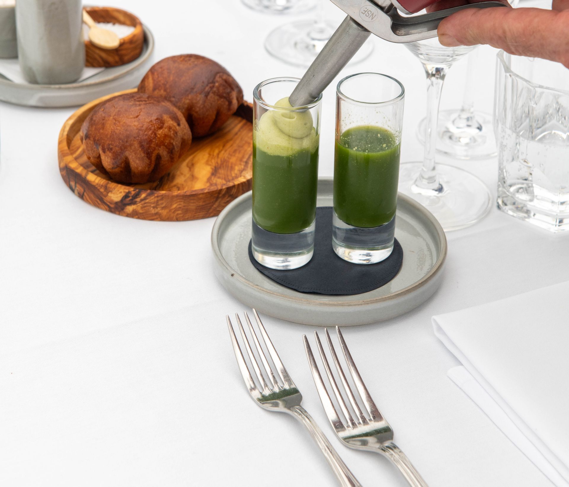 Een persoon giet groene vloeistof in twee shotglaasjes