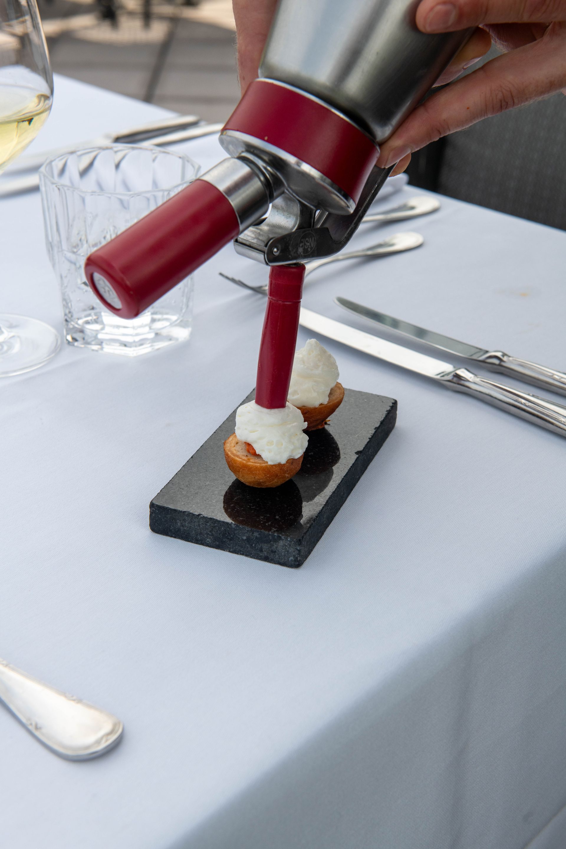 Iemand giet slagroom over een dessert op tafel.