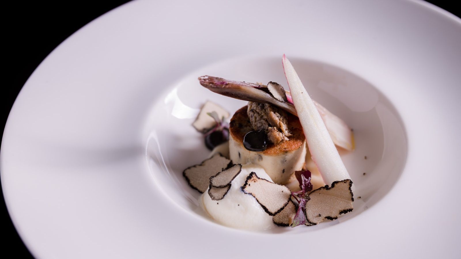 Een close-up van een wit bord met eten op een tafel.