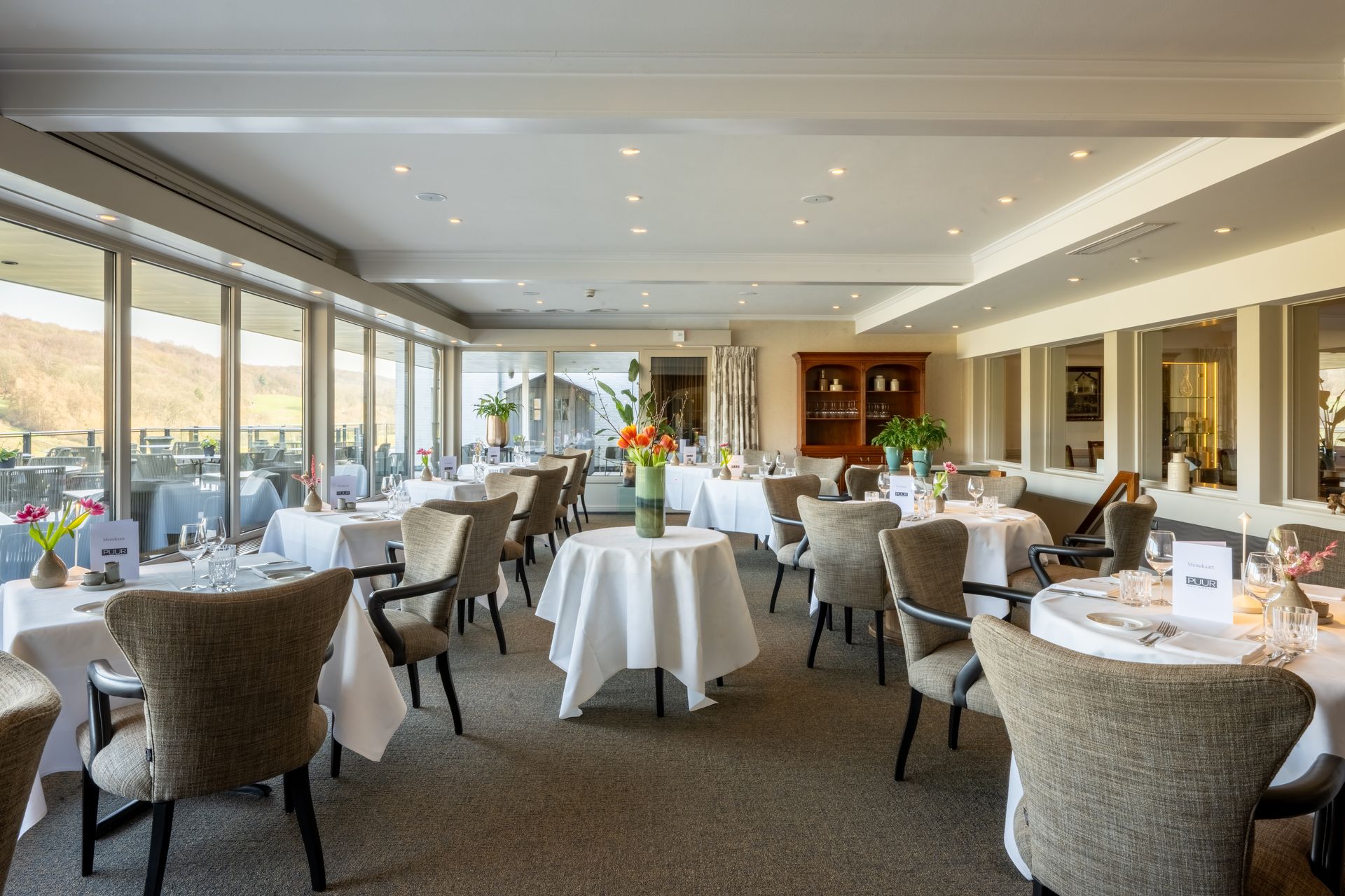 Een restaurant met tafels en stoelen die klaar staan ​​voor een maaltijd.