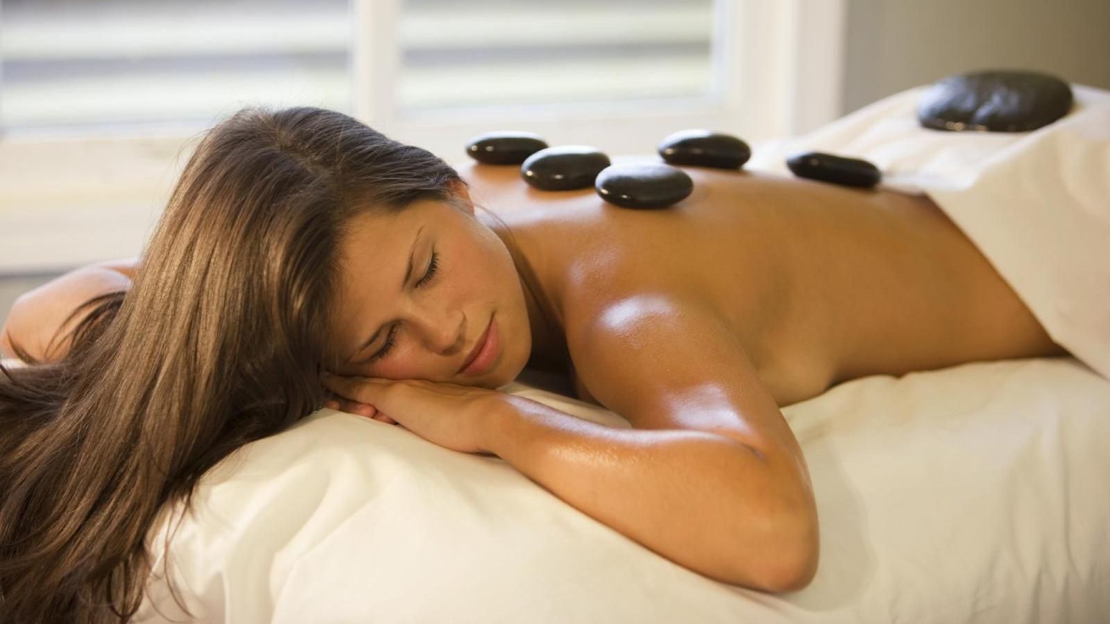 Eine Frau liegt auf einem Bett und bekommt eine Hot-Stone-Massage.