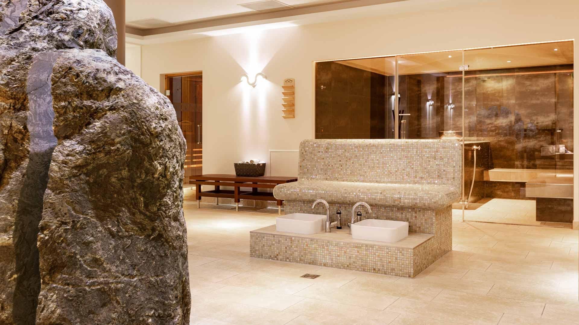 In een kamer met een bank en wastafels staat een standbeeld van een man.