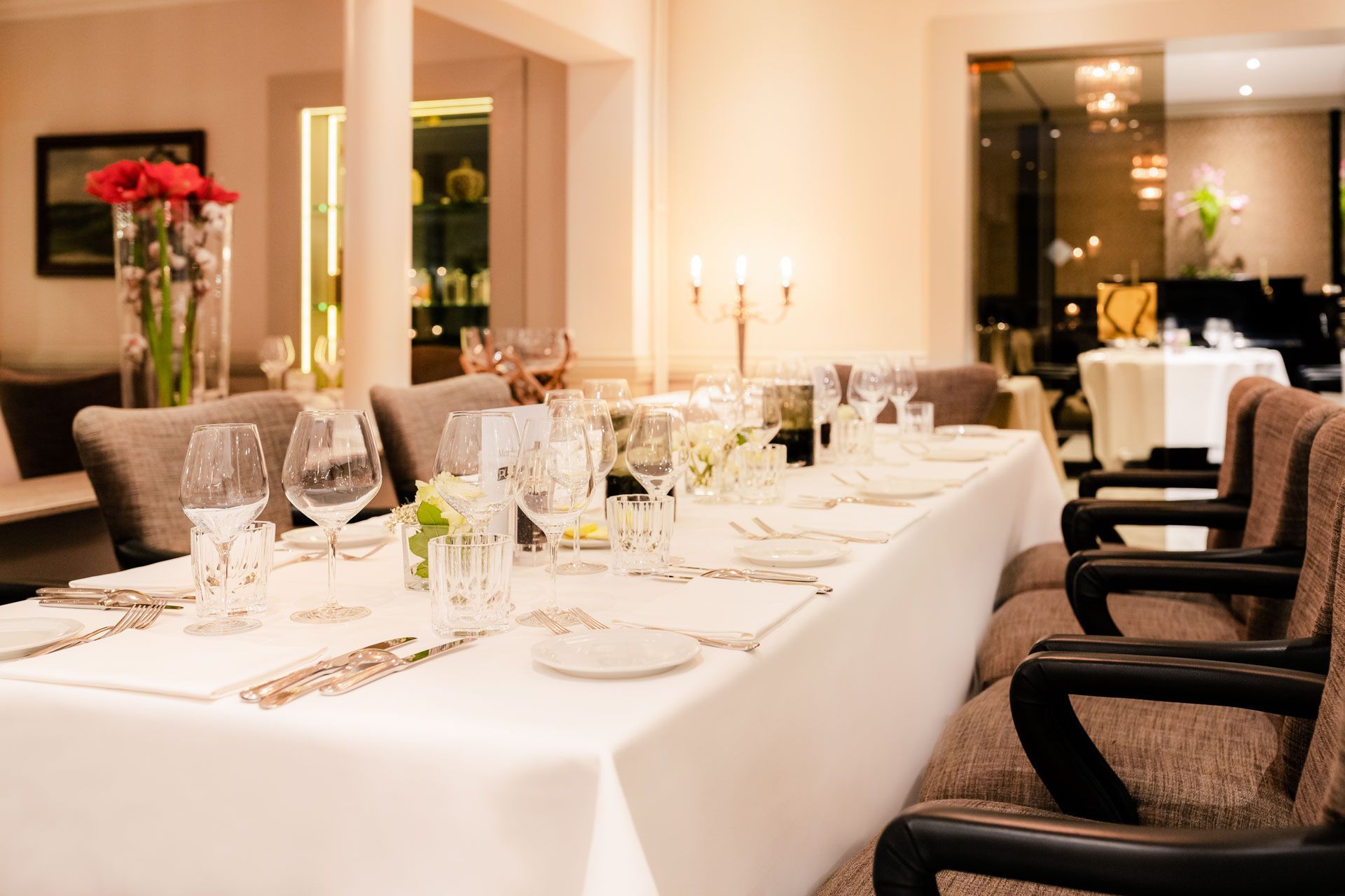 Een lange tafel met een wit tafelkleed en wijnglazen erop