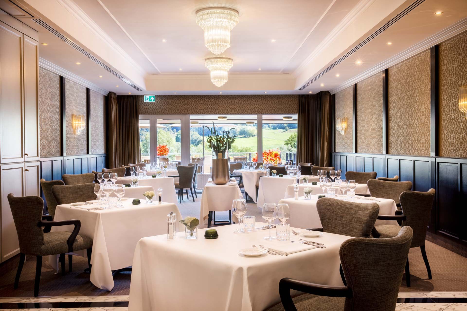 Een grote eetkamer met tafels en stoelen en een kroonluchter die aan het plafond hangt.