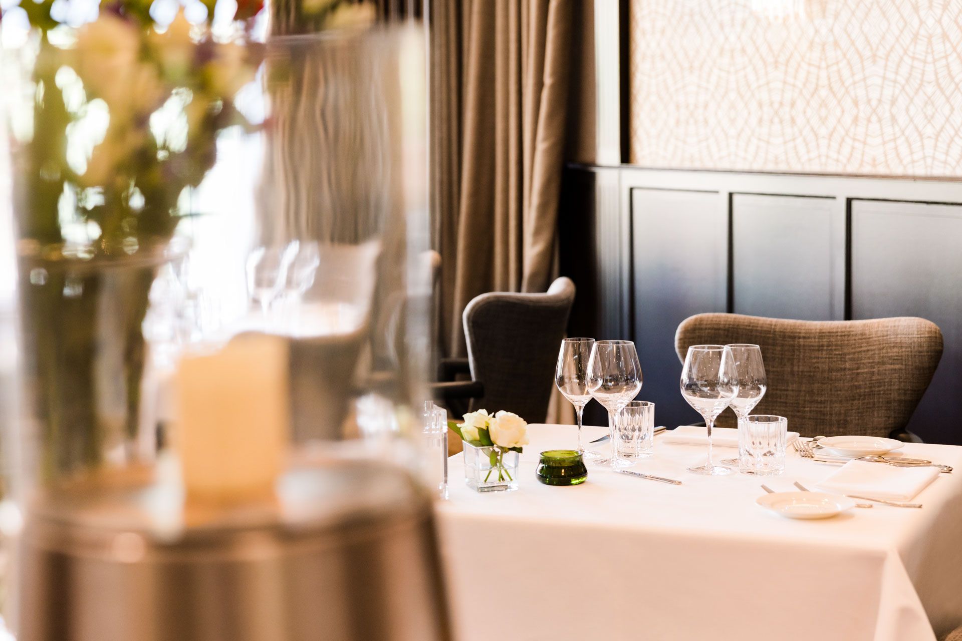 Een gedekte tafel voor een diner in een restaurant, met een vaas met bloemen op de voorgrond.