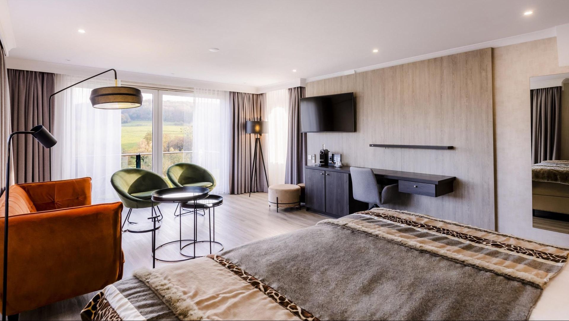 Een hotelkamer met een groot bed, een bank, stoelen en een televisie.