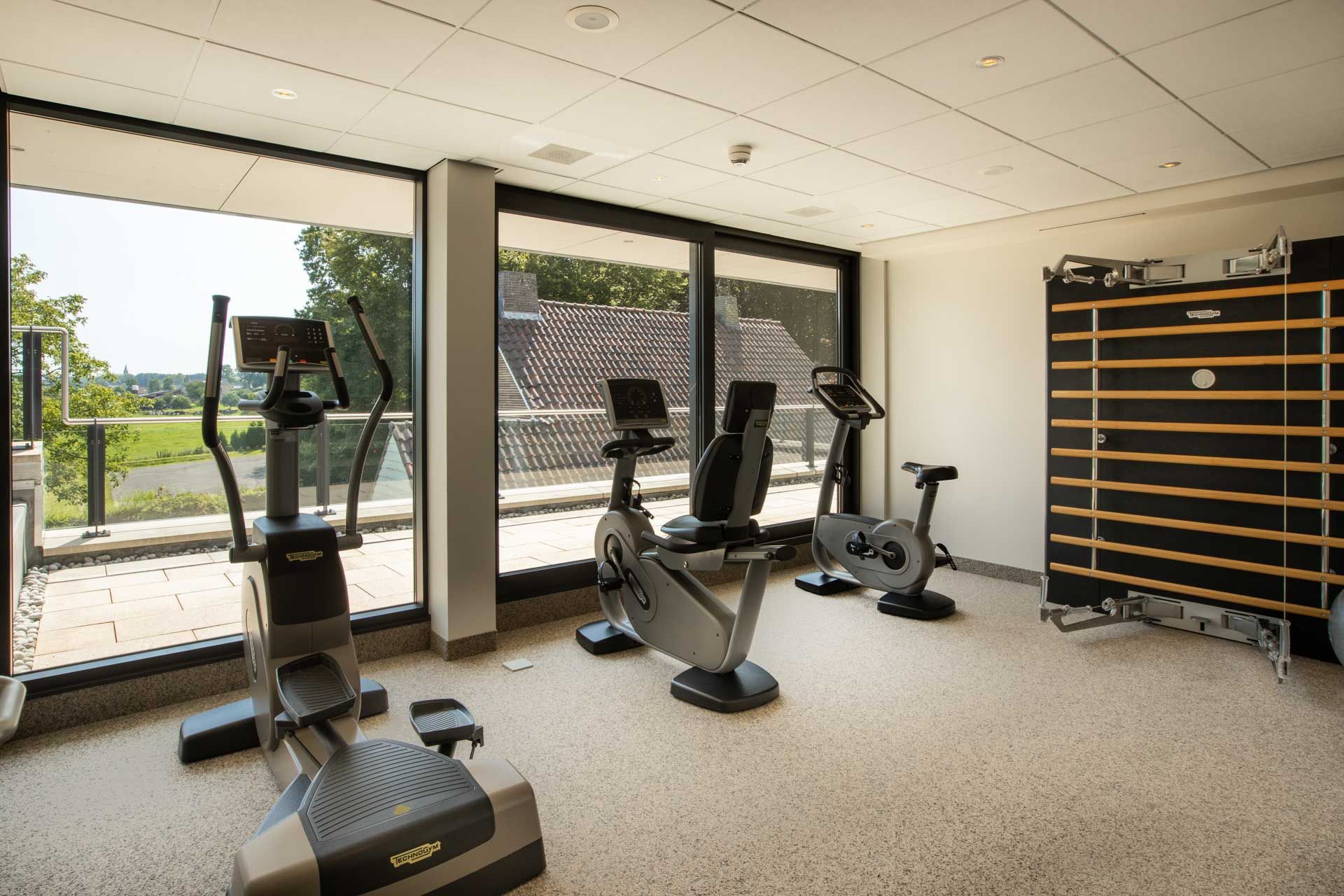 Ein Fitnessstudio mit vielen Trainingsgeräten und vielen Fenstern.