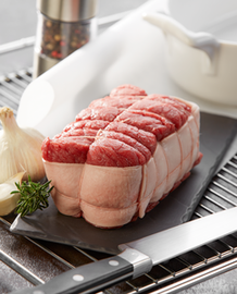 Un rôti de bœuf sur une planche en ardoise avec un couteau de cuisine à côté.