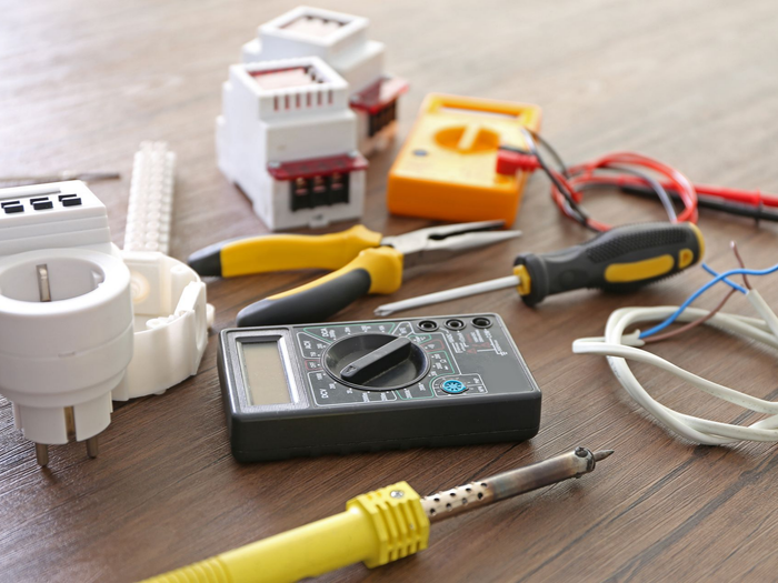 Divers outils électriques et connecteurs de fils disposés sur une table en bois.