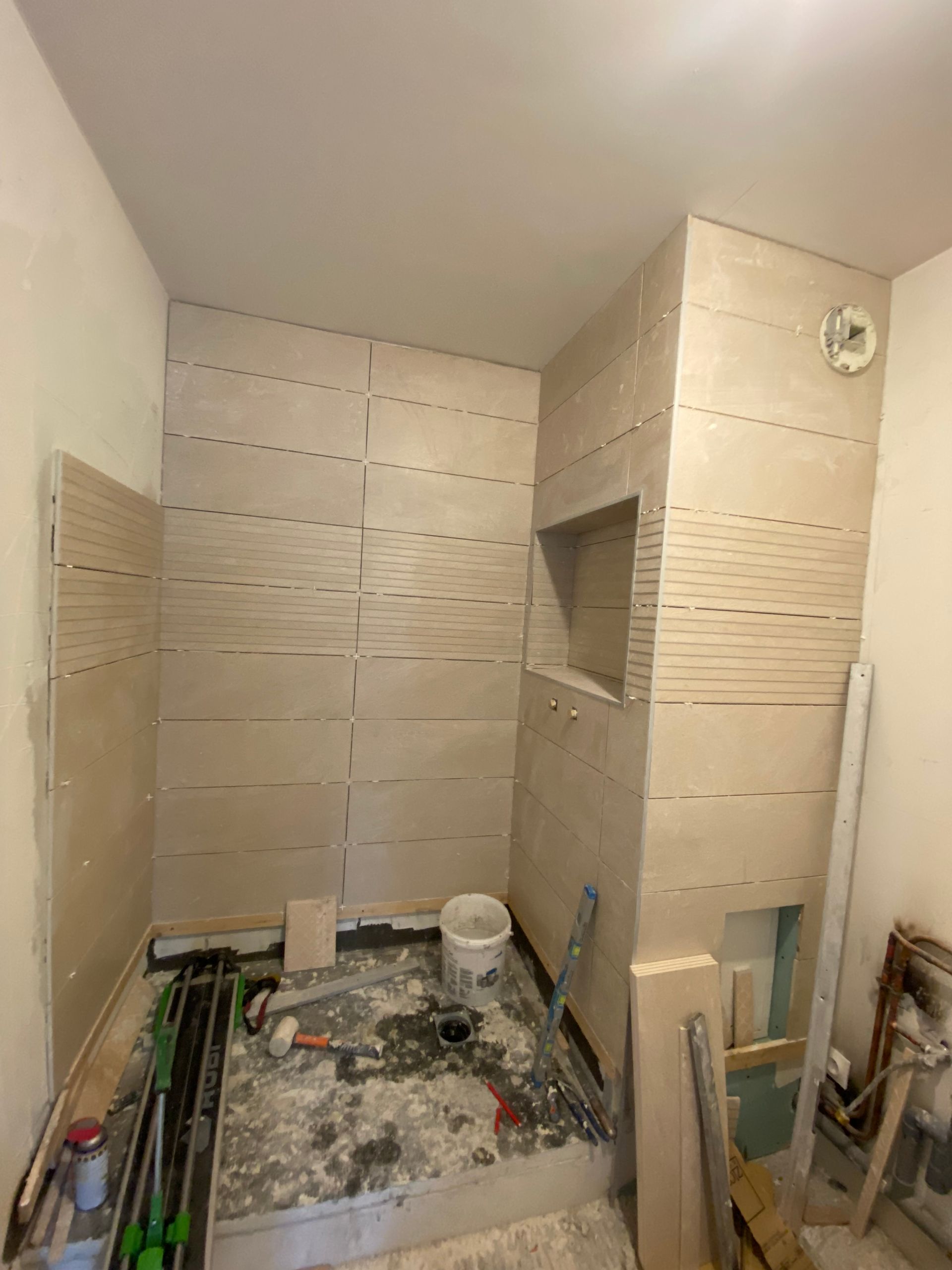 Salle de bains carrelée en rénovation, avec outils apparents.
