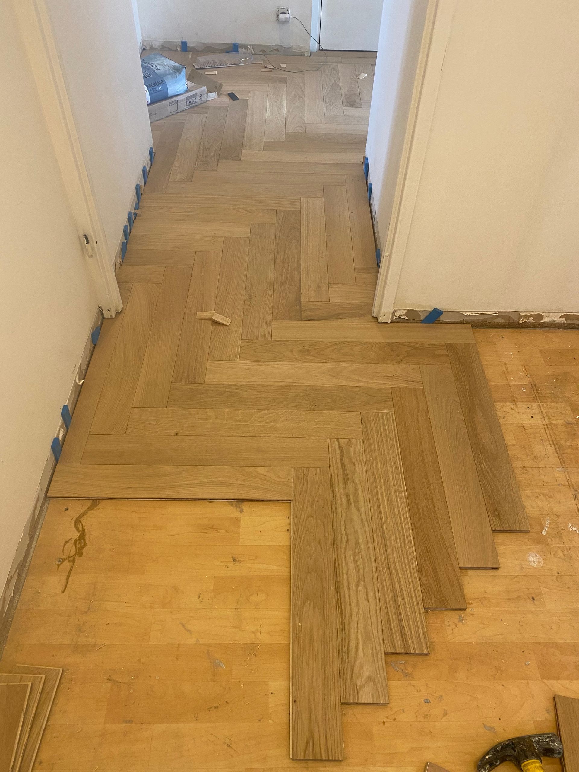 Pose d'un parquet à chevrons dans un couloir.