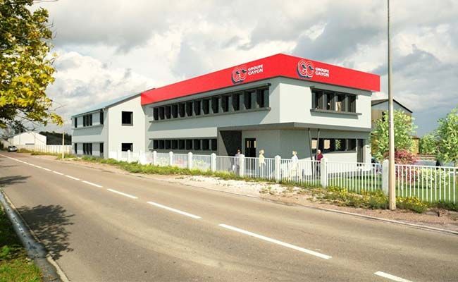 Bâtiment commercial de deux étages avec un toit rouge, des murs blancs, situé en bord de route sous un ciel nuageux.
