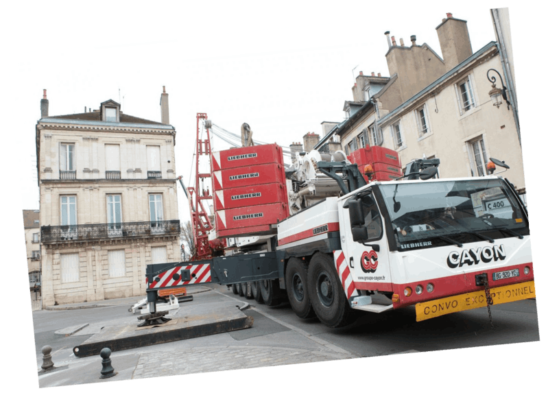 Grue dans une rue de la ville ; la grue rouge et blanche se trouve près d'un bâtiment.