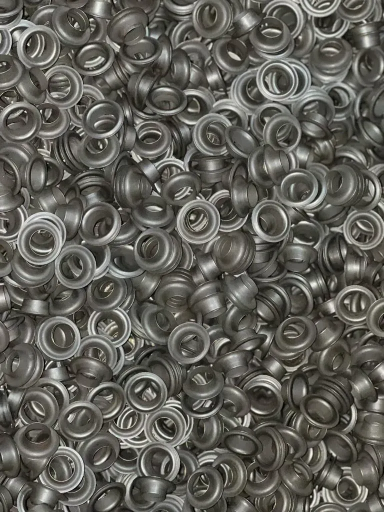Pila de pequeños ojales metálicos plateados, esparcidos al azar.