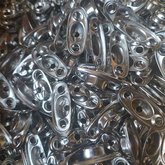 Pila de piezas metálicas brillantes, plateadas y oblongas, con dos orificios para tornillos y un orificio central.
