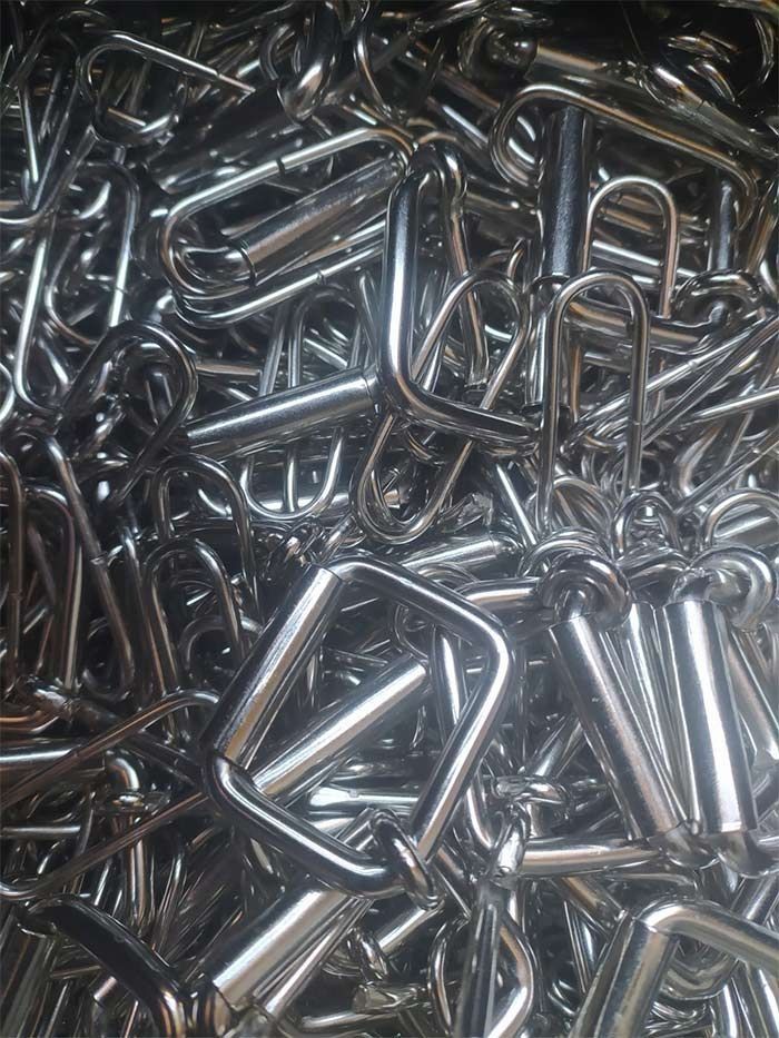 Pila de anillos en D de metal plateado brillante, probablemente componentes de hardware.