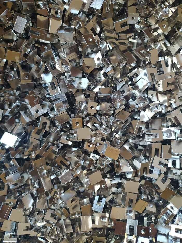 Pila de clips pequeños, brillantes y metálicos, de forma cuadrada y con una apertura rectangular.