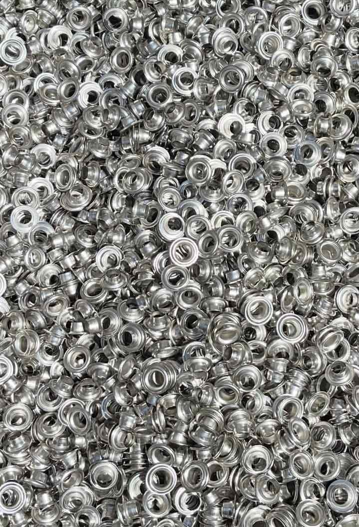 Pila de pequeños remaches metálicos plateados, muy juntos.