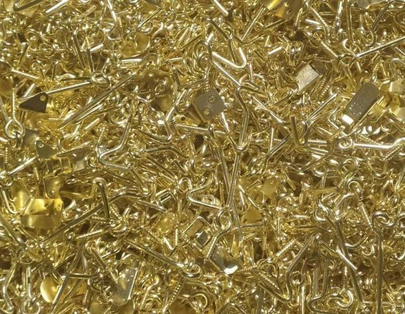 Pila de pequeños objetos metálicos dorados y brillantes, posiblemente herrajes.