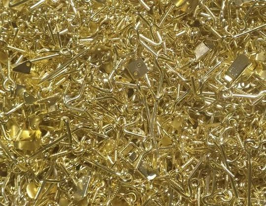 Pila de pequeños objetos metálicos dorados y brillantes, posiblemente herrajes.