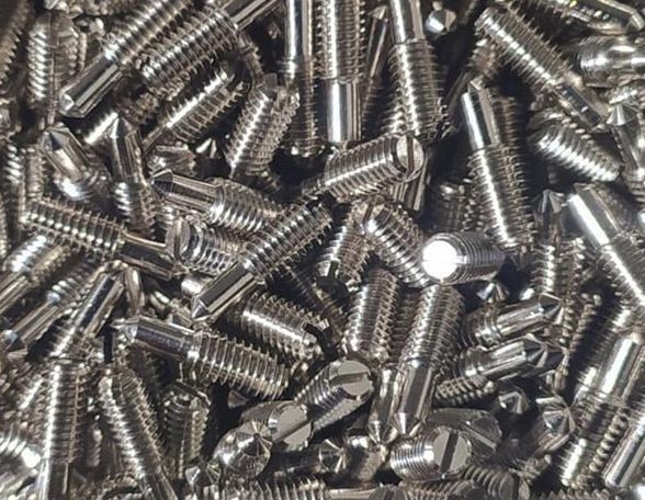 Pila de tornillos plateados brillantes con distintos tipos de cabeza.