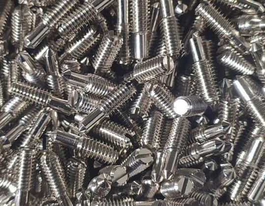 Pila de tornillos plateados brillantes con distintos tipos de cabeza.