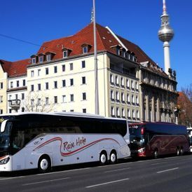 drei Busse parken hintereinander an einer Straße, Häuser im Hintergrund