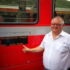 Mann vor einem roten Zug mit Schriftzug
