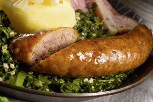 Teller mit Grünkohl, Wurst, Kartoffeln und Schinken.