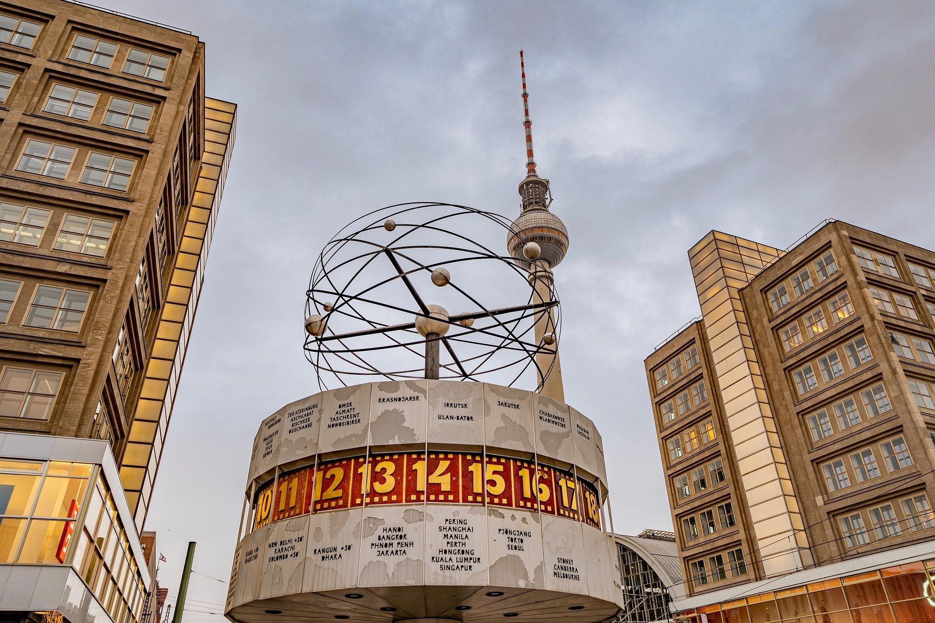 Stadtplatz mit einer großen digitalen Uhreninstallation zwischen hohen Gebäuden und einem Turm im Hintergrund