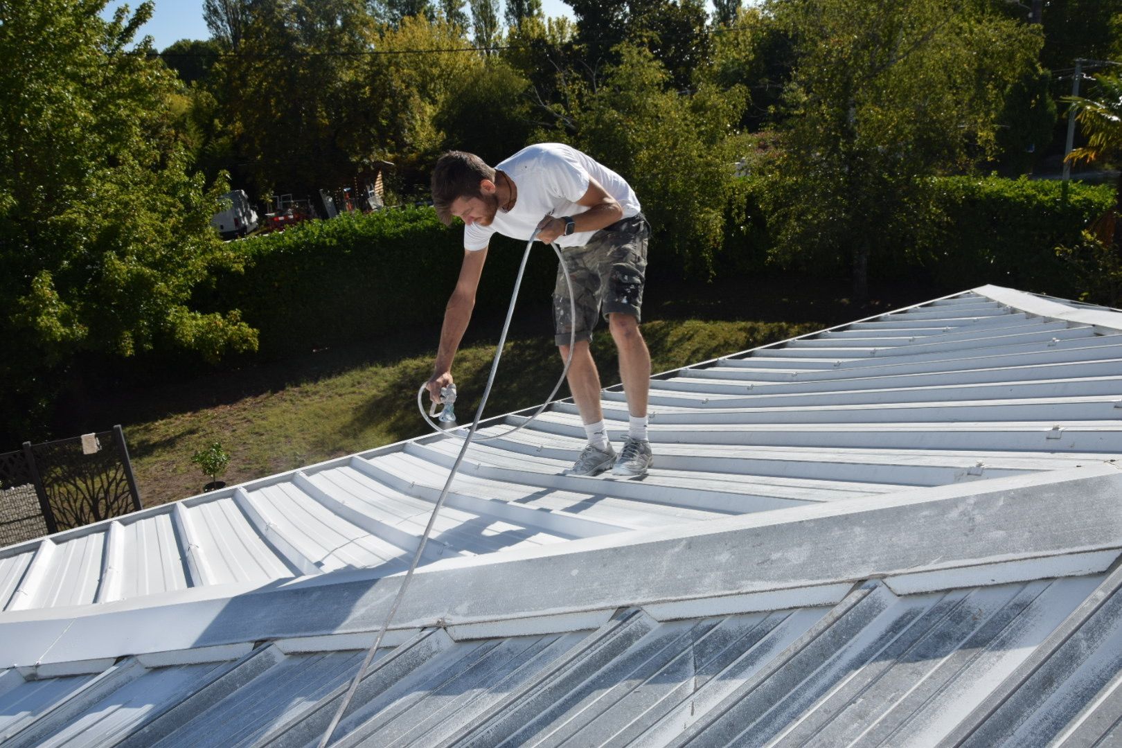 Couvreur appliquant la peinture en projection