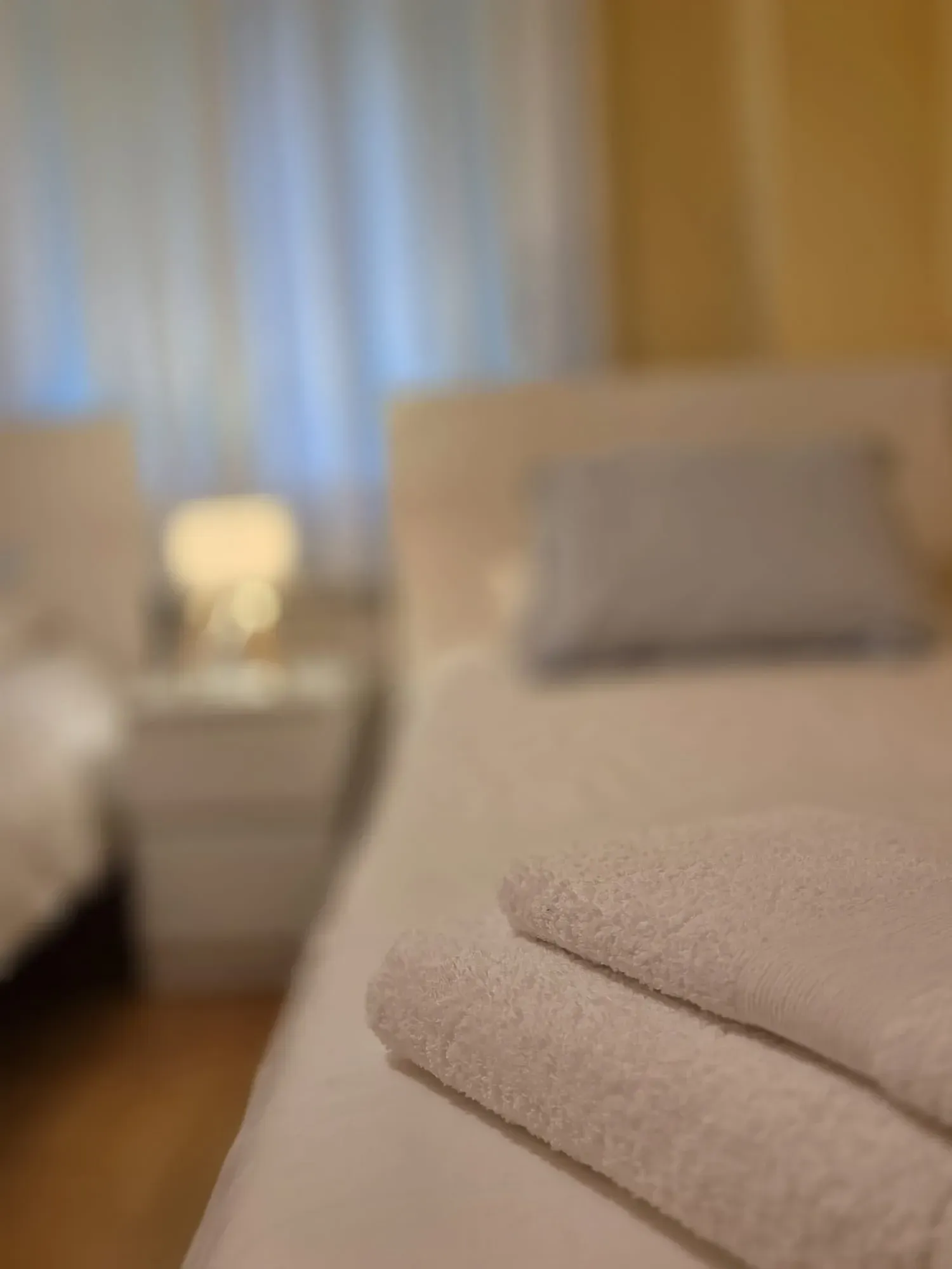Toallas cuidadosamente dobladas sobre una cama en una habitación con iluminación tenue.