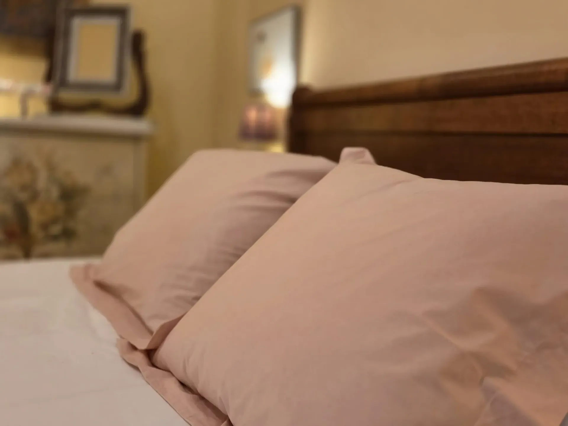 Almohadas rosas sobre una cama en una habitación con iluminación tenue.