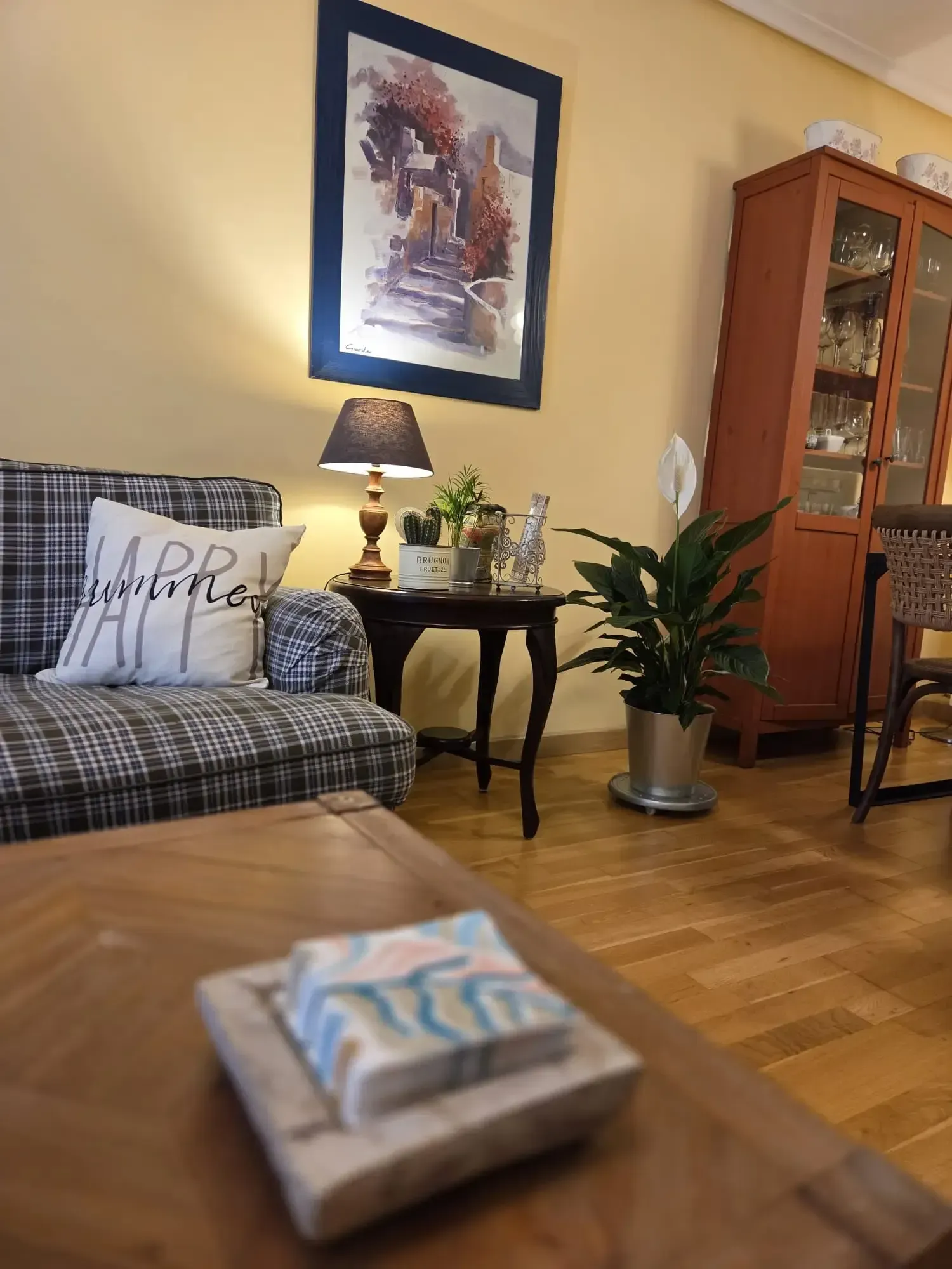 Acogedora sala de estar con sofá a cuadros, mesa auxiliar, lámpara, planta en maceta